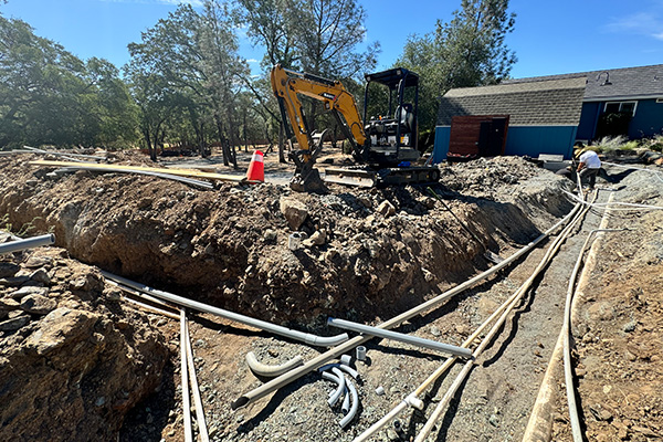Complex underground drainage pipe network under construction with excavator on site